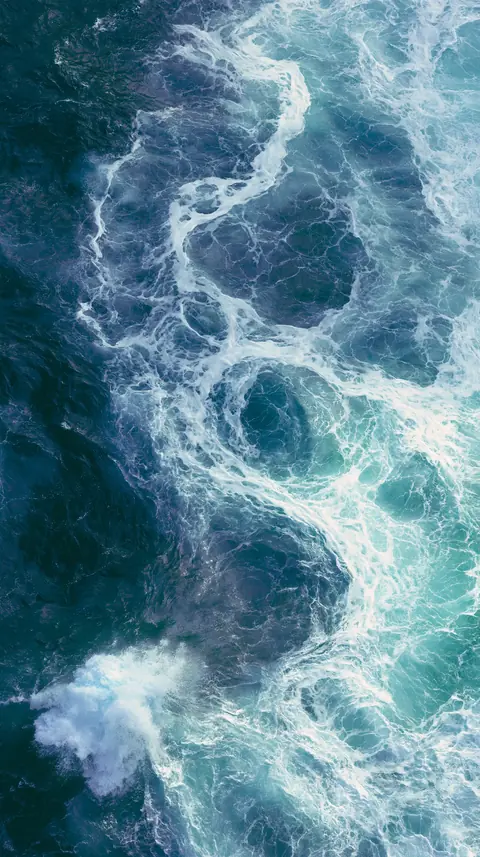 An aerial top-down view of deep blue ocean, a connective surface.